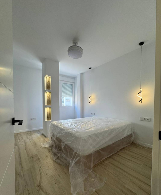Dormitorio renovado con iluminación suspendida